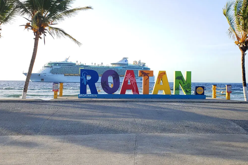 Guests enjoying a private Roatán shore excursion at the colorful Roatán sign